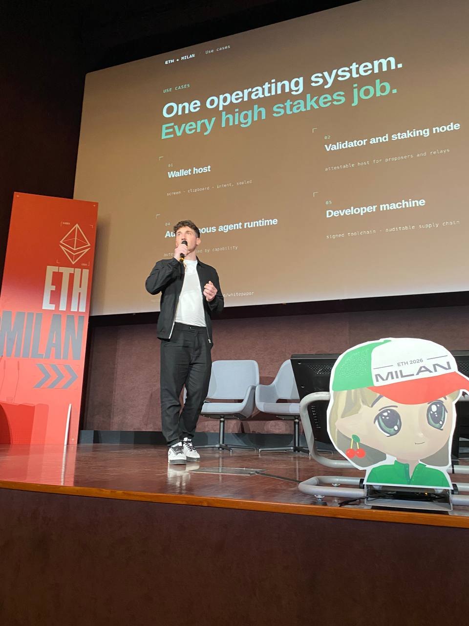 Speaking on the ETH Milan stage with the slide One operating system, every high-stakes job